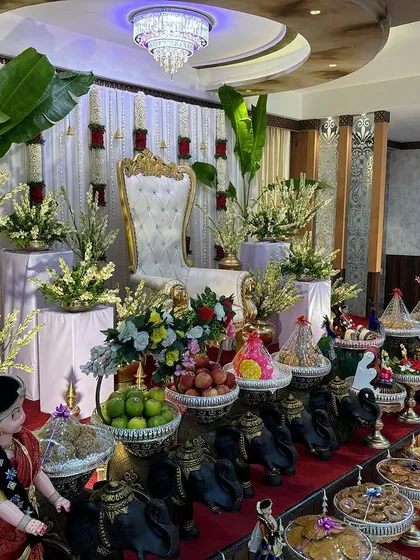 A stage with a white curtain backdrop, red rose accents, and large banana plants.