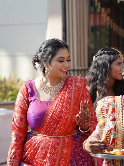 A joyful candid from a wedding celebration. Her makeup looks fresh and vibrant, and the side-belt on her lehenga adds a modern touch to the traditional outfit.