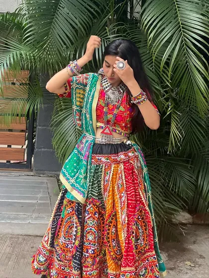 A candid moment in a beautiful multi-colored chaniya choli. The green dupatta adds a lovely contrast to the red and black base of the outfit.