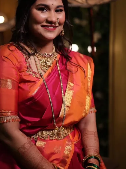 A beautifully dressed client smiling for the camera, her arms adorned with my mehndi design.