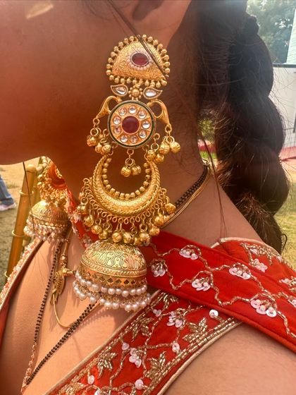 Another angle of the multi-tiered gold jhumkas, showing their intricate design and length.
