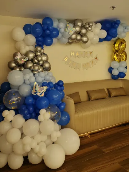 A butterfly-themed balloon arch for a birthday party at home. This arrangement in shades of blue, white, and silver is designed to fit perfectly in a living room corner, adding a festive touch without taking over the space.