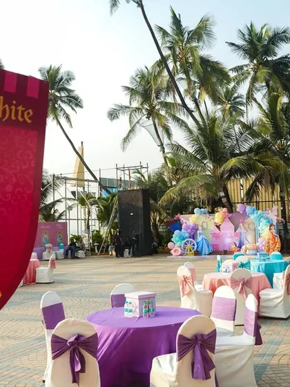 Themed seating areas at the outdoor princess party, with a Snow White banner and purple table settings.