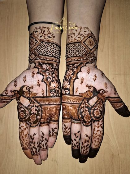 A unique siders design with artistic flair. The pattern features stylized peacocks with leafy vines on the fingers and a mix of geometric and floral work on the back of the hand.