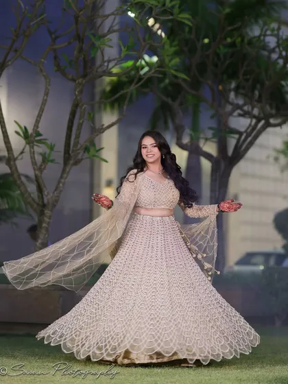 A joyful outdoor portrait of the bride twirling in her lehenga, her happiness radiating from the photo.