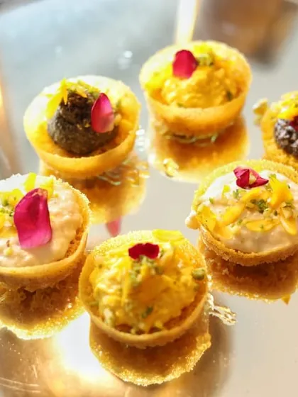 These bite-sized tartlets are filled with a variety of sweet creams and garnished with delicate rose petals. Served on a mirrored tray, their reflections create a beautiful and abundant display.