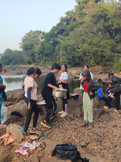 Participants prepare their meal by the riverside, learning to be resourceful in the outdoors.