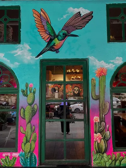 A full shot of the restaurant entrance, where a large painted hummingbird welcomes guests.