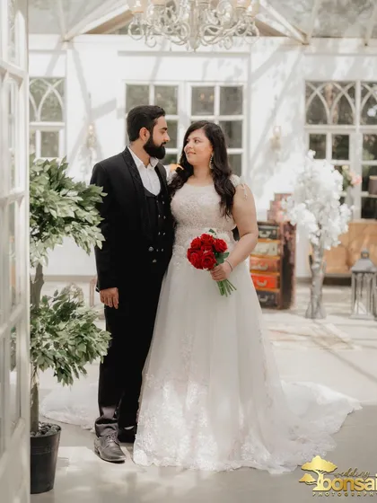 A classic portrait of the couple inside the elegant Picture Villa. The red bouquet provides a striking contrast against the bride's white gown.