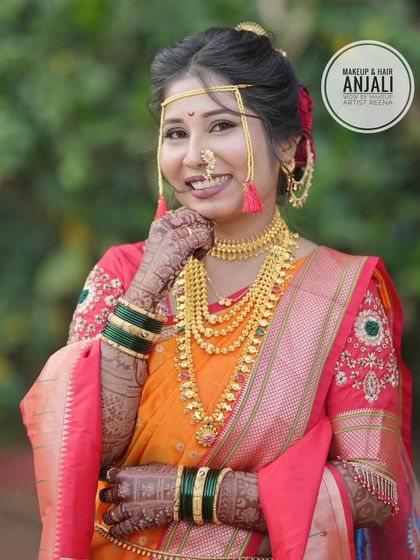 The complete Maharashtrian bridal look for Akshaya, featuring a beautiful orange and red saree, layered gold necklaces, and green glass bangles.