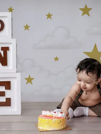 The moment of truth. A baby curiously reaches out to touch the birthday cake for the first time, a key moment in any cake smash photography session.