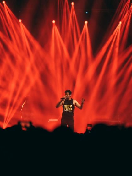 A dramatic shot of Salim Merchant under red spotlights, creating a powerful visual for the audience at ISB.