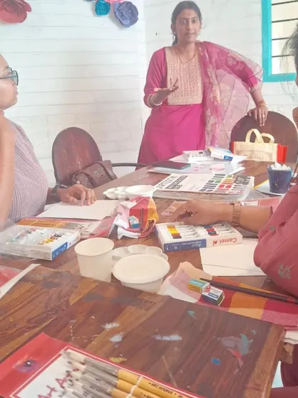 A view of the Awakening Shakti workshop in session, with art supplies spread across the table as participants listen to the instructor's guidance.