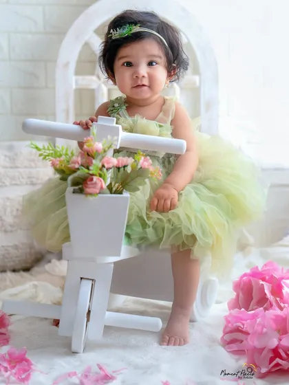A quiet moment of sweetness during a first birthday shoot. This little girl in her green dress looks so angelic sitting on her floral tricycle.