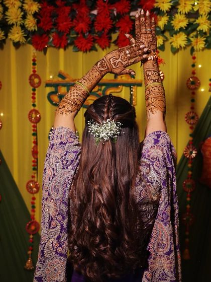A creative pose showing off the intricate mehndi design and a beautiful bridal braid.