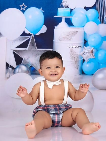 A joyful moment from a cake smash session, with the birthday boy laughing happily. The blue and silver star-themed background adds a festive touch to this celebratory portrait.