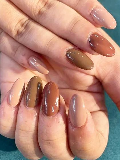 A chic and trendy set featuring different shades of brown and nude polish on each nail for a "gradient" manicure look.