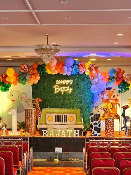 I can handle large-scale events in banquet halls and on stages. This grand jungle-themed first birthday features a lush greenery backdrop, a full stage setup with animal props, and a vibrant balloon arch to welcome guests.