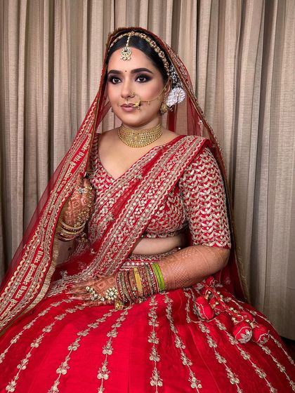 A full-length view of this stunning bride in her traditional red attire. The makeup is designed to be both glamorous and timeless, ensuring she looks and feels her best.