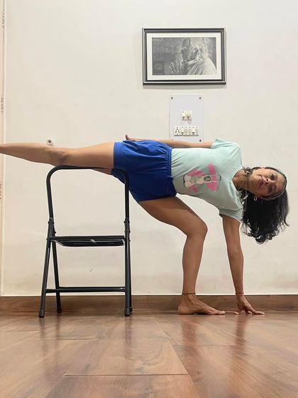 Ardha Chandrasana (Half Moon Pose) is practiced here with the support of a chair. The chair helps with balance, allowing the student to focus on extending the spine and opening the hips and chest.