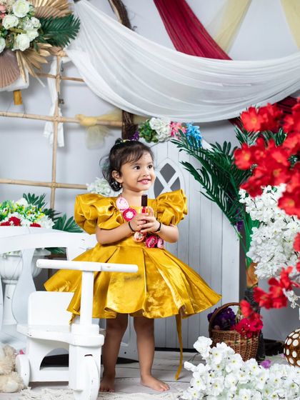 A happy girl in her party dress, holding a small prop.