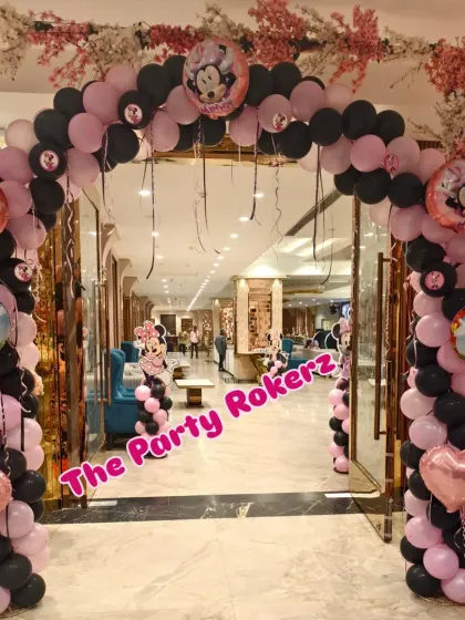 The entrance arch for the Minnie Mouse party, decorated in the classic pink and black color scheme with character foil balloons.