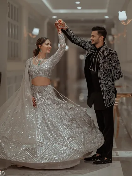 A beautiful shot of the couple twirling in a grand corridor, the bride's silver lehenga catching the light perfectly.