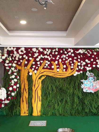 The complete stage for a Krishna-themed naming ceremony, including the backdrop and the floral cradle.