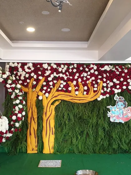 The complete stage for a Krishna-themed naming ceremony, including the backdrop and the floral cradle.