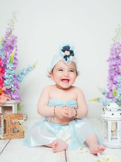 A joyful baby clapping her hands during her first birthday photoshoot.