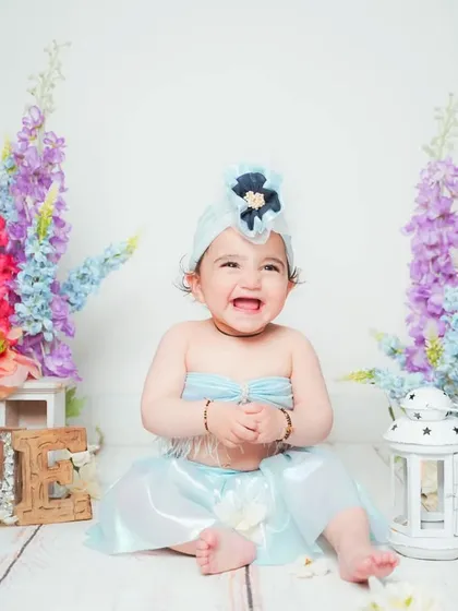 A joyful baby clapping her hands during her first birthday photoshoot.