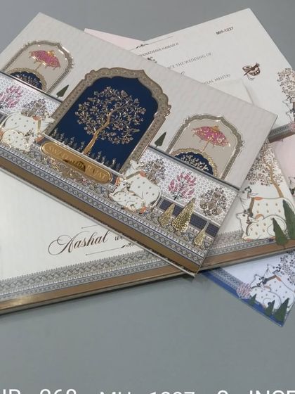 This invitation features a beautiful tree of life motif under a royal arch, with cows illustrated in the foreground. The design is unique and rooted in Indian cultural art.