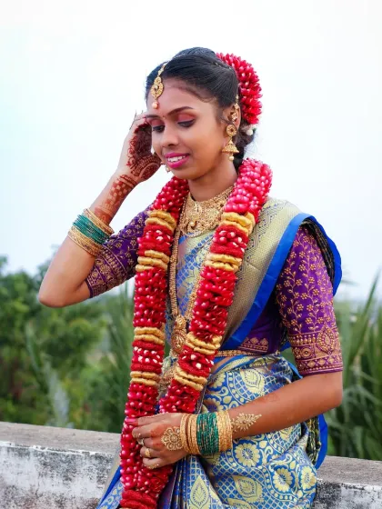A classic portrait pose from a puberty ceremony. The subject is adorned with a beautiful flower garland, and the photo captures the vibrant colors of her attire and the happy expression.