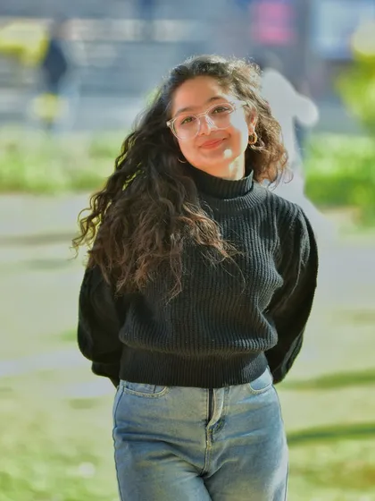 A relaxed and happy portrait with a soft, sunny background. Her gentle smile and casual pose make this a very approachable and warm lifestyle shot.