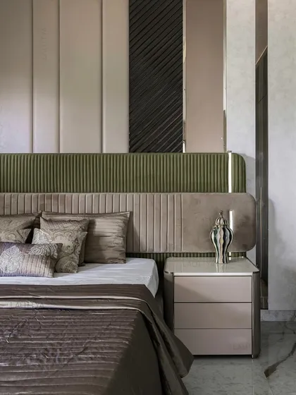 A close-up of the layered bed back in this bedroom, wrapped in muted olives and velvety taupes. The combination of fluted and paneled upholstery creates a design with quiet strength, perfect for rest.