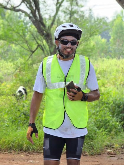 A smiling volunteer in a high-visibility vest, enjoying the greenery along the Rajyotsava ride route. Our volunteers are the unsung heroes of every event.