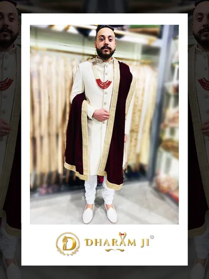 A happy client trying on his wedding attire. He's wearing a classic cream sherwani paired with a deep maroon velvet stole, showcasing a rich and elegant combination.