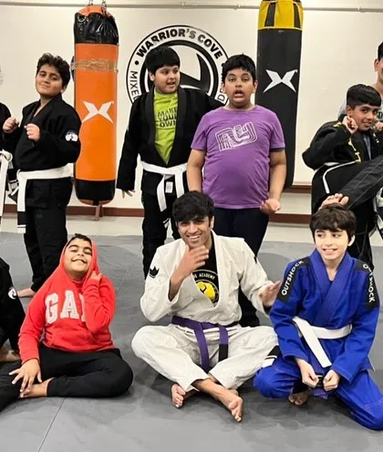 A proud group of our BJJ students with their coach. Wearing the gi (the traditional uniform) instills a sense of identity and pride in their practice.