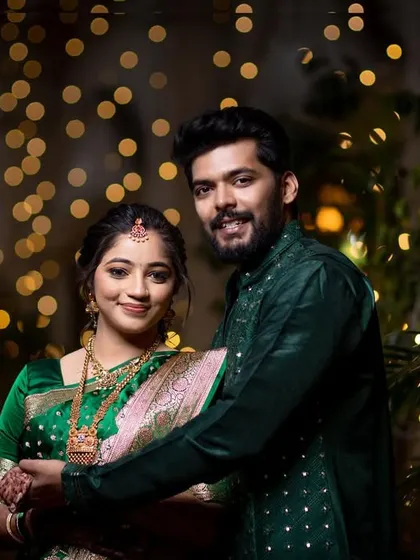 A smiling couple portrait against a warm, festive background of bokeh lights.