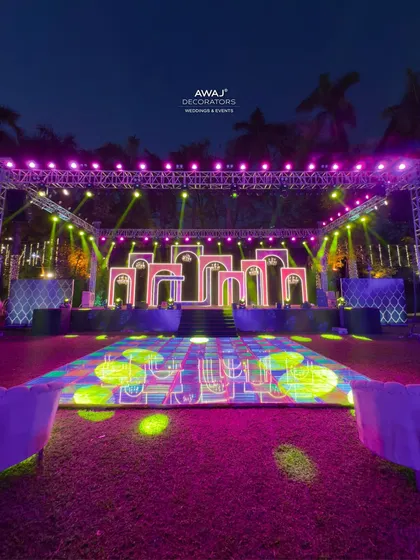 The full Sangeet stage and dance floor, with vibrant, colorful lighting creating an electrifying atmosphere.