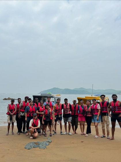 A group photo on a sandy beach, with our transport boats in the background, after a fun day of sea activities.
