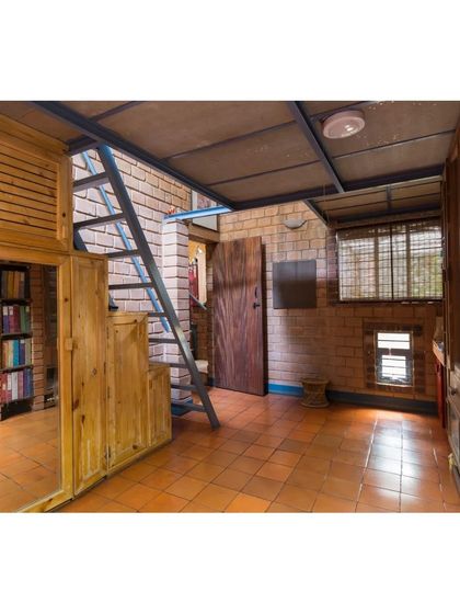 This bedroom demonstrates how we integrate storage and structure, with wooden cabinets built into the mezzanine support. The narrow windows are strategically placed to ensure privacy while allowing for natural light, reducing the need for concrete lintels.