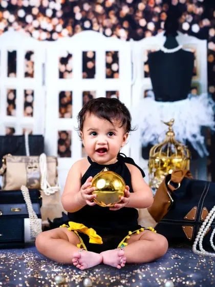 A big, happy smile from the baby boy in the middle of the chic black and gold setup.