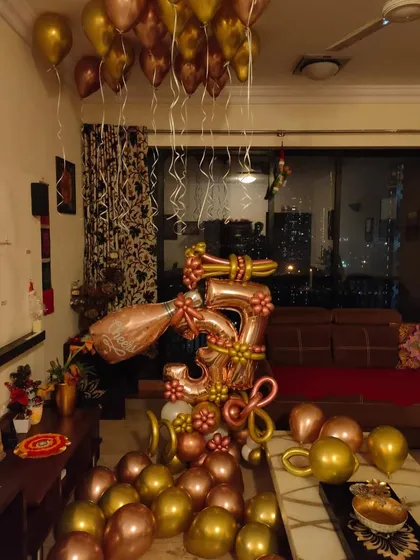 Celebrating a 3rd anniversary with a fun and festive balloon arrangement at home. This custom rose gold setup includes a large number '3' sculpture, a popping champagne bottle balloon, and coordinating balloons filling the space.