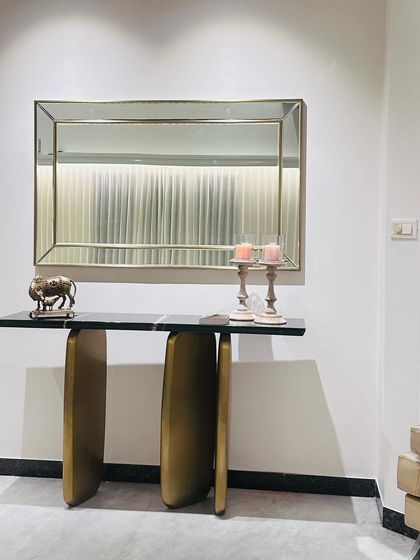 Another view of the custom console table, highlighting its slender profile and the beautiful contrast between the dark marble, the warm gold base, and the light-colored walls.