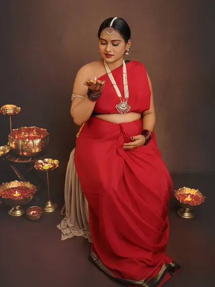 Holding a diya, the lamp of life, this portrait is rich with symbolism. The warm glow illuminates her face, creating a serene and deeply traditional maternity photo.