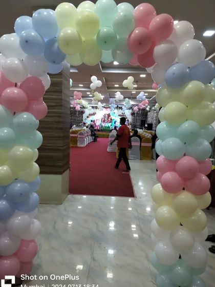 A pastel-colored balloon arch at the entrance of the hall for the Krishna-themed naming ceremony.