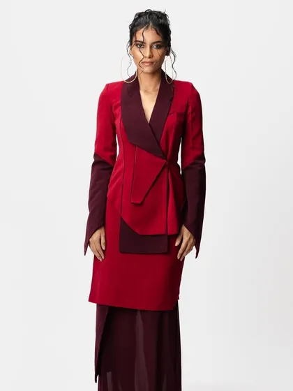 A full-length view of a high-fashion look for a designer brand. I created a messy, artistic updo with loose, wet-look tendrils to complement the structured, two-tone red blazer.
