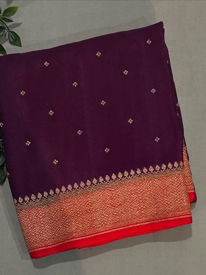 A deep wine-colored Banarasi crepe saree with a contrasting red and gold border.