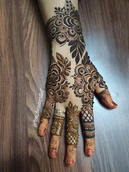 A beautiful and intricate back-hand design. The contrast between the dark, filled leaves and the delicate linework creates a stunning effect.